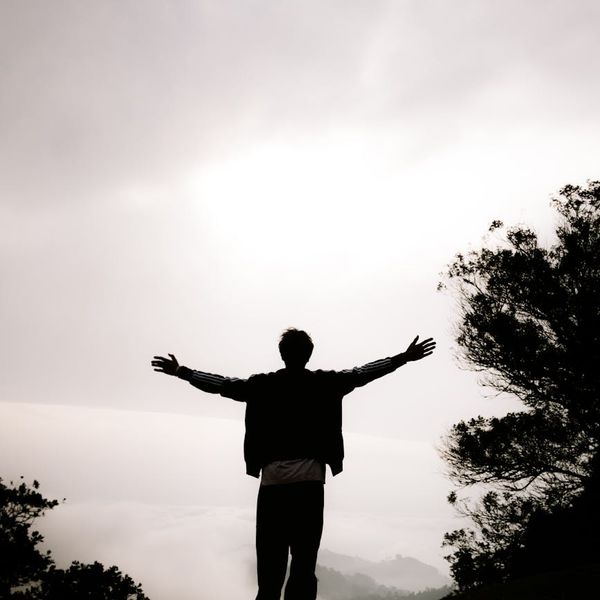 Person meditating peacefully outdoors at sunrise with a calm expression.
