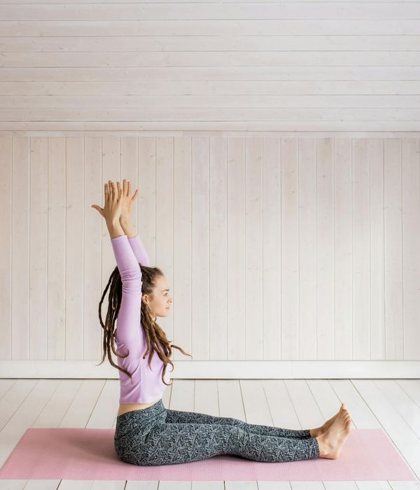 Woman performing a calm yoga stretch in a serene environment with lilac light.